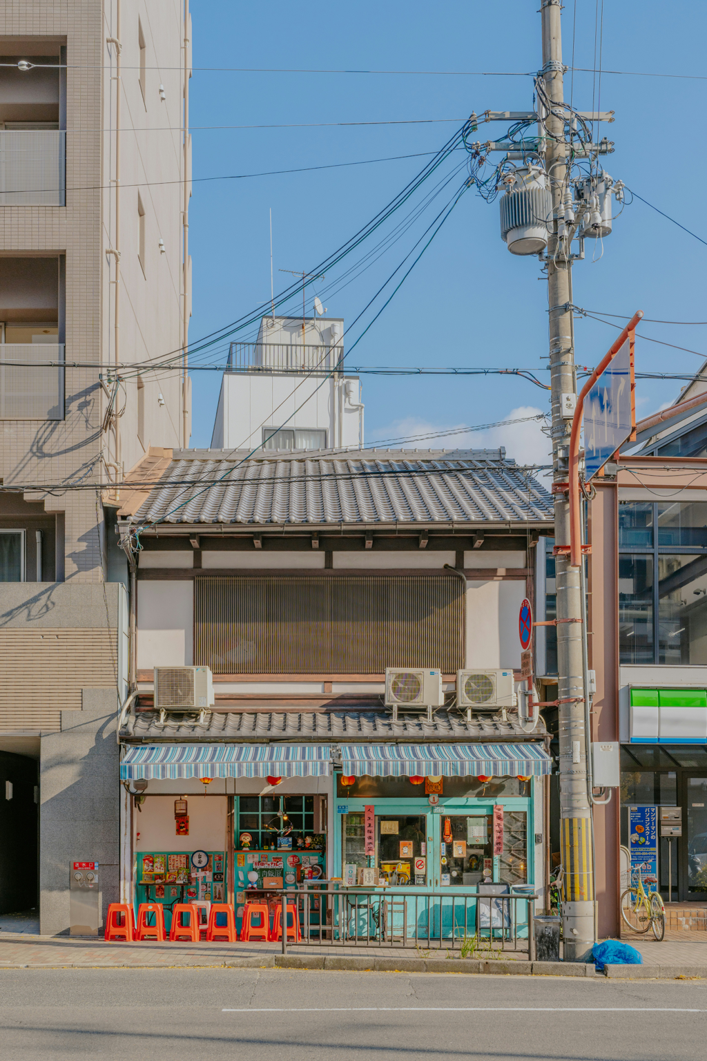 電柱と雑居ビルに囲まれた、レトロな構えの実店舗の外観
