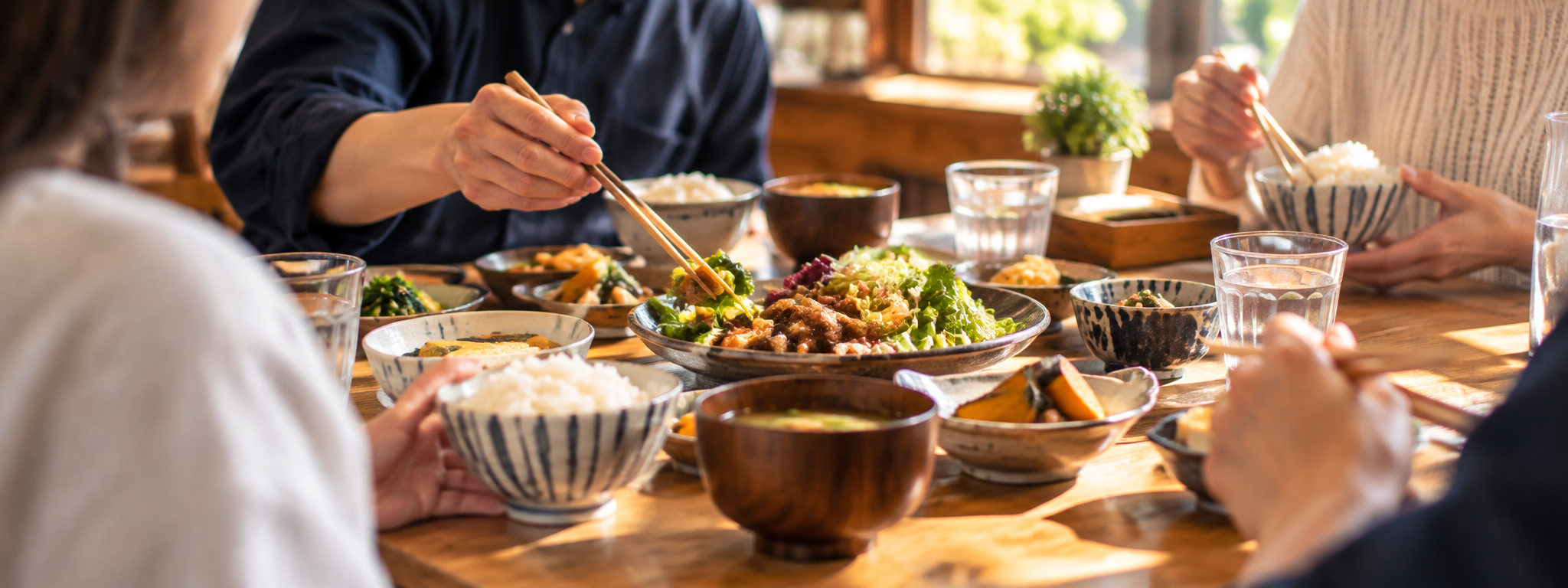 家族や友人と食卓を囲み、箸を伸ばして料理を分け合う様子